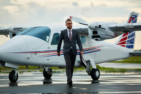 Бизнесмен с портфелем, идущий с самолета — стоковое фото