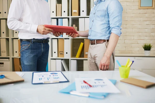 Employee giving clipboard to his colleague — Stock Photo, Image