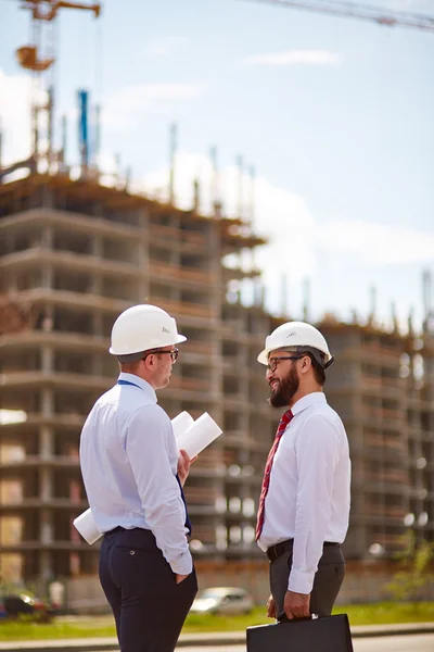 Geschäftsleute in Helmen vor unvollendetem Bau — Stockfoto