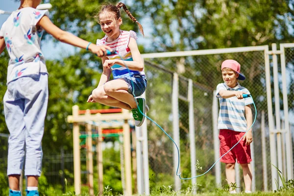 Flickan hoppar över hoppa rep med vänner — Stockfoto