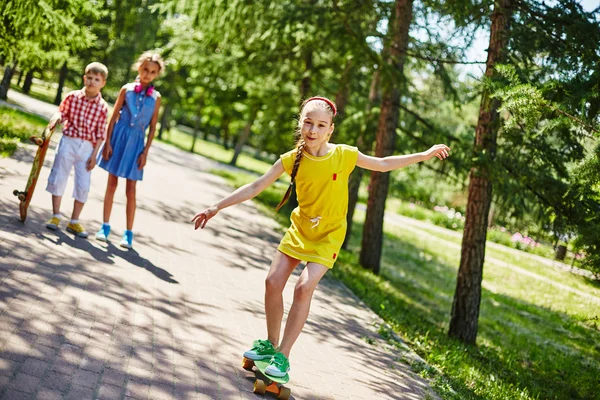 Barátai parkban gördeszka lány — Stock Fotó