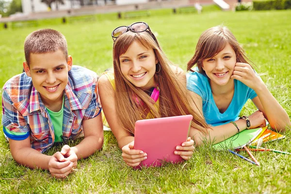 Adolescentes acostados en la hierba con la tableta — Foto de Stock