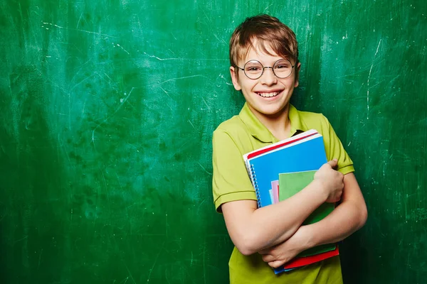 Jongen met boeken door schoolbord — Stockfoto