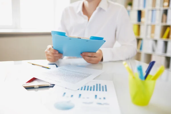 Employee with clipboard sitting at workplace Stock Image