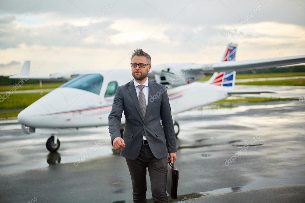 businessman with briefcase walking from airplane