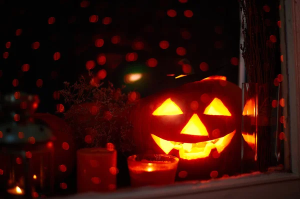 Jack-o-lantern and candles in window — Stock Photo, Image