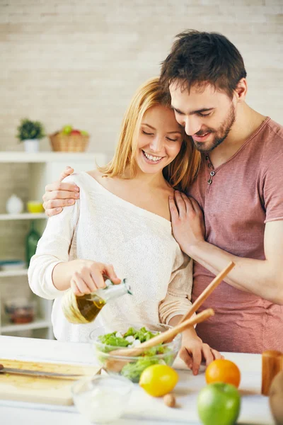 Mujer goteando aceite de oliva en ensalada — Foto de Stock