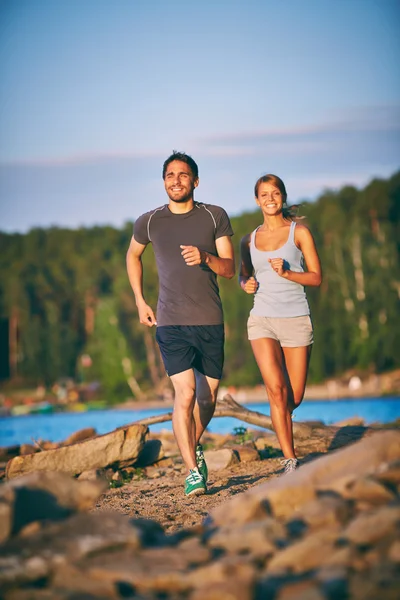 Couple running down sandy beach — 图库照片