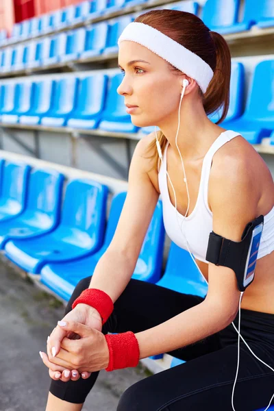 Mulher esportiva com fones de ouvido no estádio — Fotografia de Stock