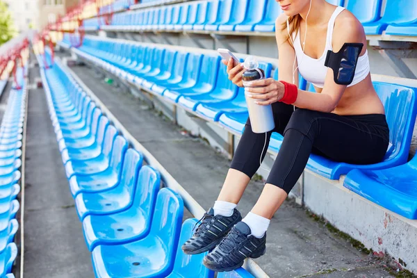 Mulher com smartphone sentado no estádio — Fotografia de Stock