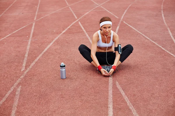 Fit woman sitting on racetrack — Stock Photo, Image