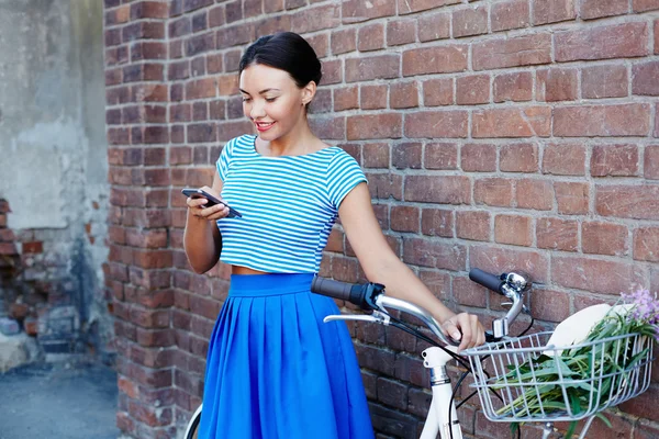 Mulher usando celular em pé perto de ciclista — Fotografia de Stock
