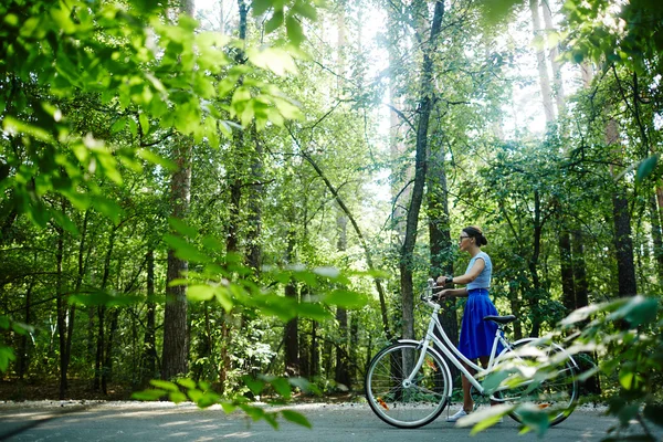 Kobieta z rowerem spaceru w parku — Zdjęcie stockowe