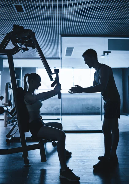 Mujer haciendo ejercicio con entrenador en el gimnasio — Foto de Stock