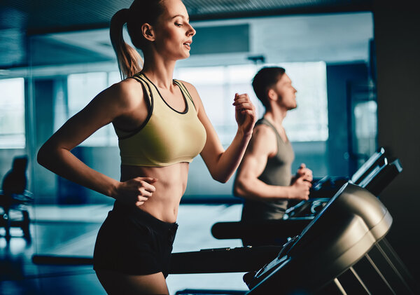 woman and man running on treadmill