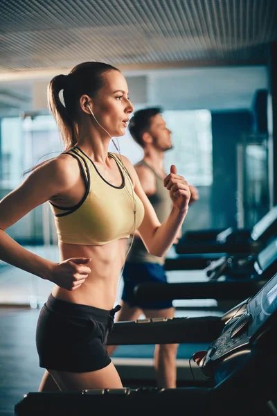 Frau mit Kopfhörern läuft auf Laufband — Stockfoto