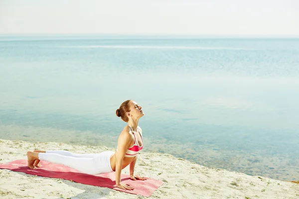 Kobieta robi ćwiczenia rozciągające na plaży — Zdjęcie stockowe