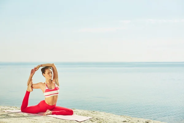 Mujer haciendo ejercicio de yoga en la playa — Foto de Stock