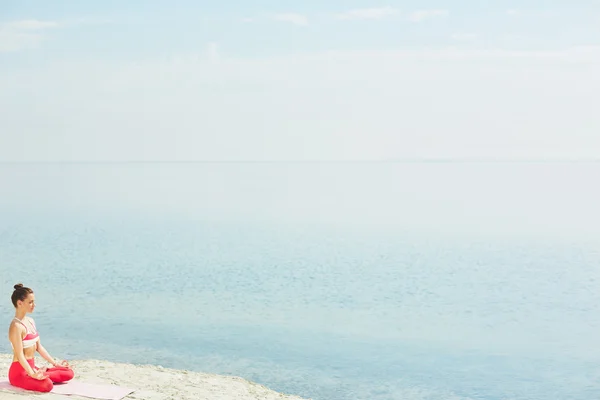 Vrouw zitten in pose van lotus op zand — Stockfoto