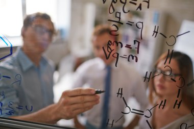 Formüller şeffaf tahtada yazılı iş adamı