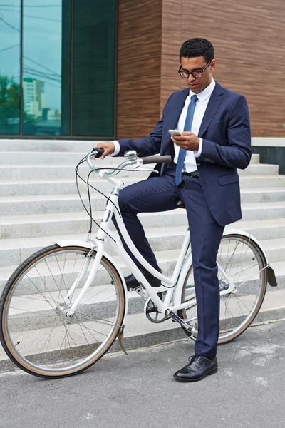 Bisiklet üzerinde otururken cep telefonu kullanarak iş adamı — Stok fotoğraf