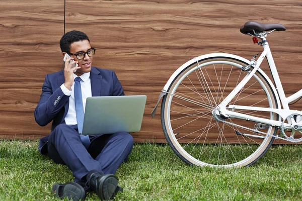 Бізнесмен з ноутбуком, що сидить на газоні — стокове фото