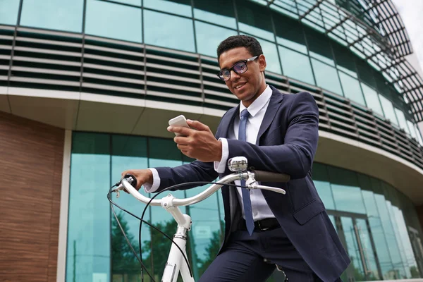 Geschäftsmann sitzt auf Fahrrad und liest SMS — Stockfoto