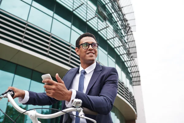 Hombre de negocios con celular en bicicleta — Foto de Stock