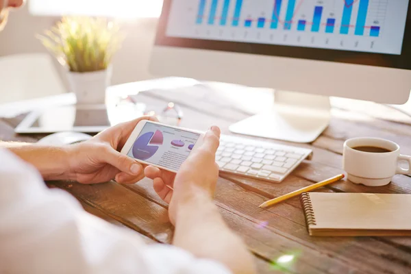 Zakenman met cellphone kijken naar diagram — Stockfoto