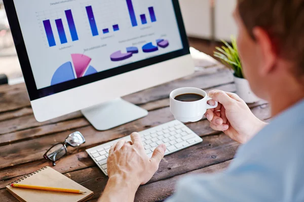 Businessman having coffee and analyzing data — Stock Photo, Image