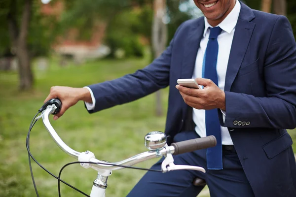 Affärsman med mobiltelefon sitter på cykel — Stockfoto