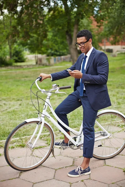 Businessman with cellphone and bicycle — Stock Photo, Image