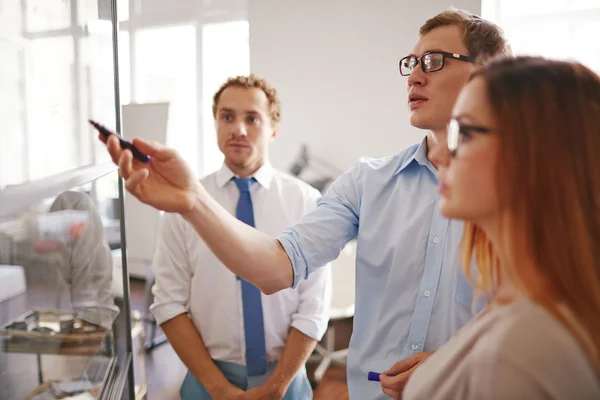 Hombre de negocios señalando la información a bordo con sus colegas — Foto de Stock