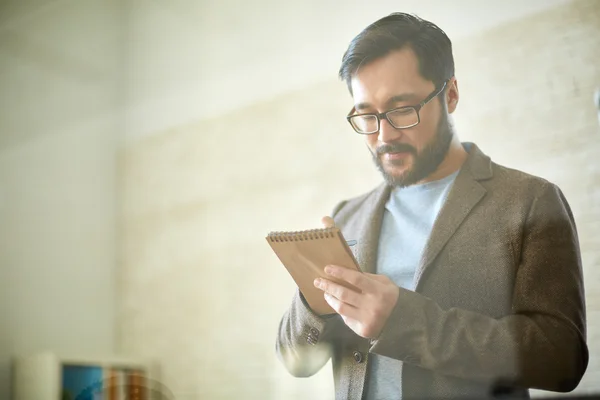 Asian businessman making notes in  notepad — Stock Photo, Image