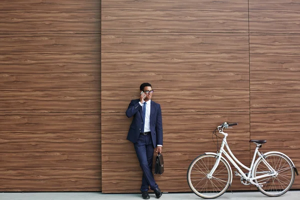 Uomo d'affari che parla al telefono con la bicicletta vicino — Foto Stock