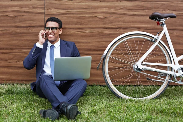 Бизнесмен с ноутбуком сидит на газоне — стоковое фото