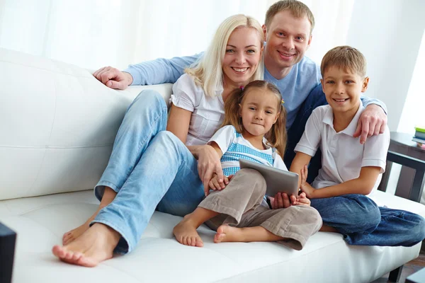 Family of four posing on sofa — Stock Photo, Image