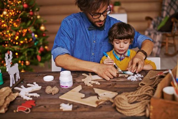 Man toont zoon hoe om te schilderen xmas speelgoed — Stockfoto