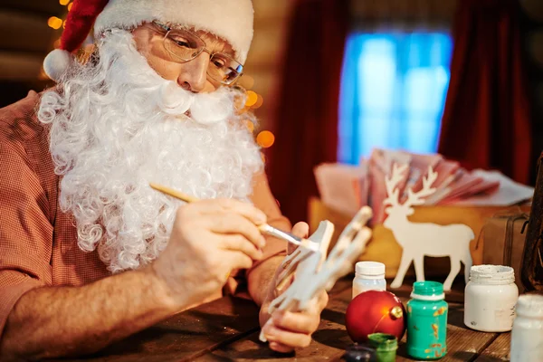 Санта-Клаус рисует деревянного оленя — стоковое фото