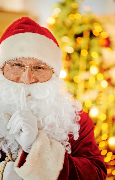 Санта-Клаус с указательным пальцем за зубами — стоковое фото