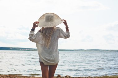 şapka ve beyaz kazak denizin kenarında kadın