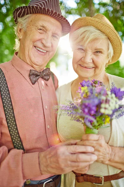 Elderly man and woman holding flowers — Stock Photo, Image