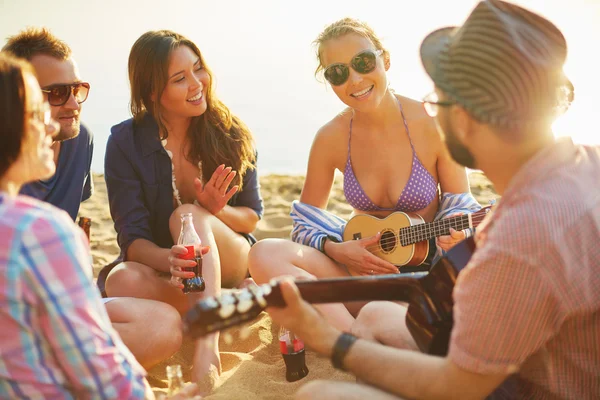 Друзья с напитками и гитарой на пляже — стоковое фото