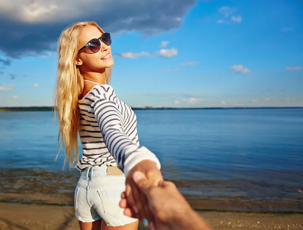 Meisje iemand met de hand te houden aan de kust — Stockfoto