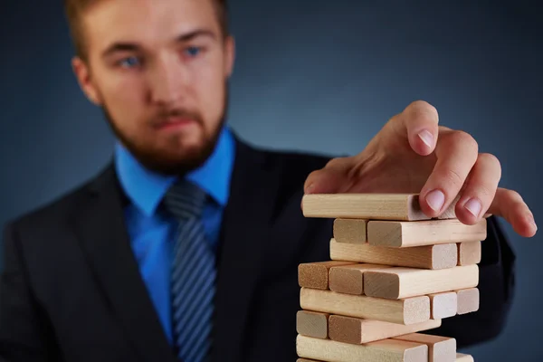 Empresario poniendo bloque en la parte superior de la torre —  Fotos de Stock