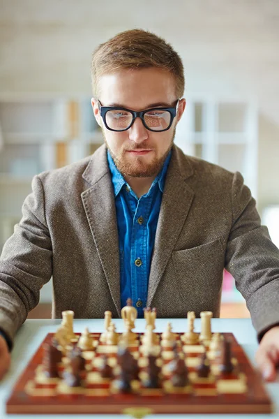 Hombre de negocios mirando el ajedrez en el tablero de ajedrez — Foto de Stock