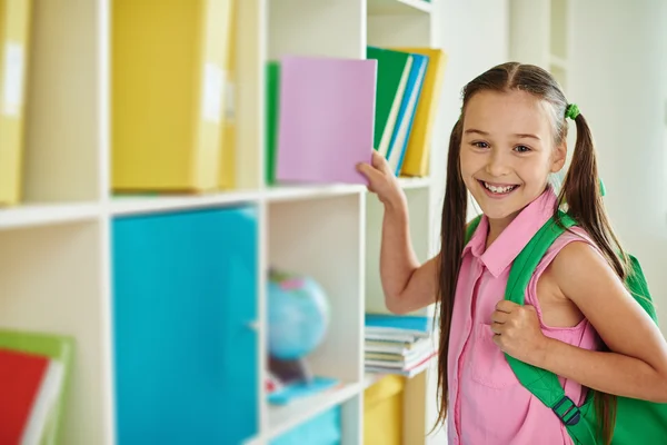 Schoolmeisje met rugzak in bibliotheek — Stockfoto