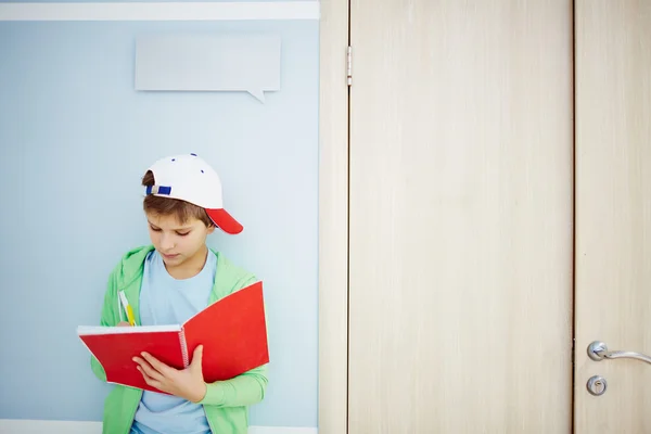 Jongen maken van aantekeningen in werkboek — Stockfoto