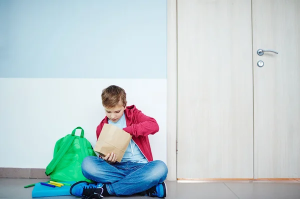 Schoolboy with paper pack taking out his lunch — Stock Photo, Image