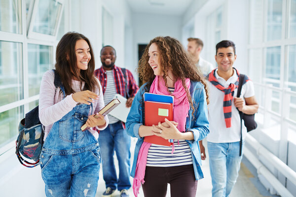 teenage girls walking along college corridor